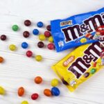 M&M's candy bags with scattered colorful candies on a white table