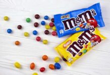 M&M's candy bags with scattered colorful candies on a white table