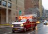 Rescuers Tunnel 100 Hours — Then This! Ambulance with flashing lights driving on a wet city street