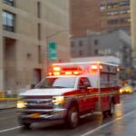 Ambulance with flashing lights driving on a wet city street