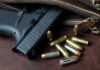 Handgun with loose ammunition beside a leather bag