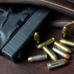 Handgun with loose ammunition beside a leather bag