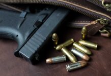 Handgun with loose ammunition beside a leather bag