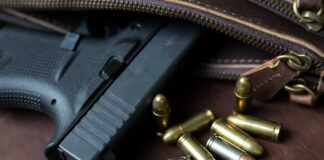 Handgun with loose ammunition beside a leather bag