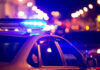 Mother’s Gun, Toddler Dead — Now What? Police car with flashing blue lights at night.