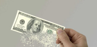 Hand holding a disintegrating hundred dollar bill.