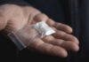Hand holding small bag of white powder.