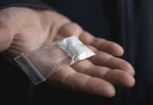 Hand holding small bag of white powder.