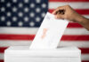 Hand inserting mail-in ballot envelope into ballot box