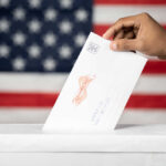 Green Light, For Now: Mail Ballot Shake-Up Hand inserting mail-in ballot envelope into ballot box