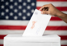 Hand inserting mail-in ballot envelope into ballot box