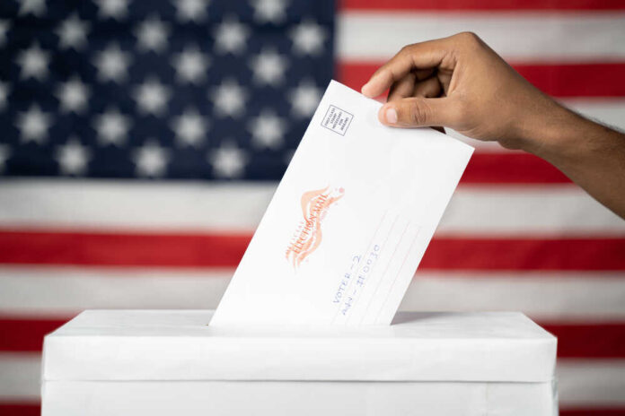 Hand inserting mail-in ballot envelope into ballot box