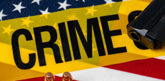 A gun and bullets on an American flag with a crime scene marker