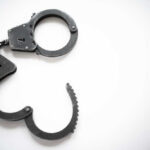 Convicted Killer Nabbed In Horrific Firestorm Open metal handcuffs on white background.