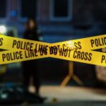 Foul Play Alarm In Vanishing Mom Investigation Police tape marking a crime scene with blurred figures in the background