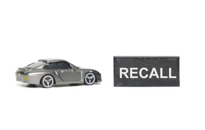 A,Picture,Of,Car,Diorama,Miniature,With,Recall,Word,At A miniature gray sports car next to a black sign that reads 'RECALL'