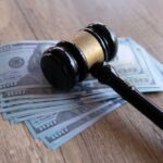 Court Slices Jones Payout — But Why? Judge’s gavel resting on a stack of US hundred-dollar bills