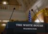 Press podium with the White House sign and an American flag in the background