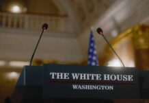 Sudden Podium Exit Stuns West Wing Press podium with the White House sign and an American flag in the background