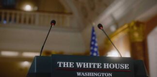 Press podium with the White House sign and an American flag in the background