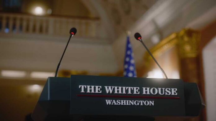 Press podium with the White House sign and an American flag in the background