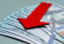 Jobs Shock: Payrolls Turn Negative Red downward arrow on U.S. dollar bills