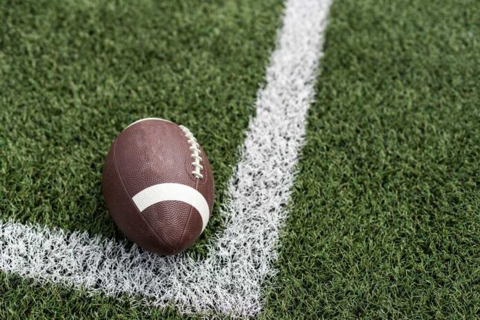 Football player in a red jersey kneeling on the field