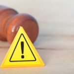 Judge’s Pause Scrambles Texas–Minnesota Extradition Yellow warning triangle with exclamation mark beside a wooden gavel