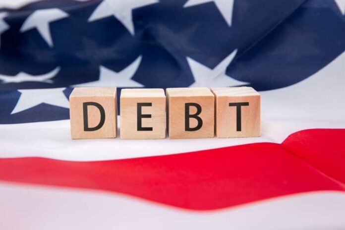 Wooden blocks spelling 'DEBT' on an American flag background