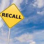 Mystery Meat Floods Stores — Recall Details Yellow sign with RECALL text against blue sky.