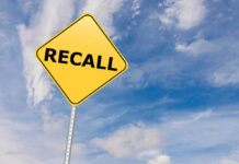 Yellow sign with RECALL text against blue sky.