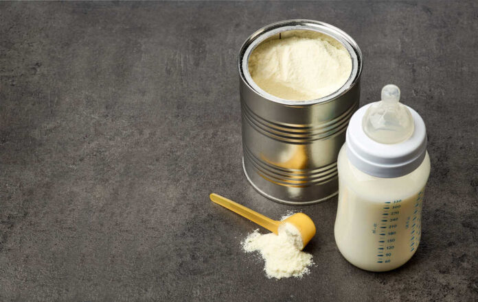A can of powdered baby formula next to a feeding bottle with milk