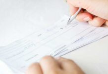 Person signing a check on a white background.