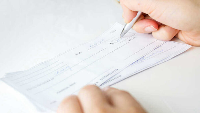 Person signing a check on a white background.