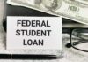 A sign reading 'Federal Student Loan' next to a stack of money and a pen