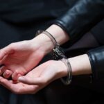Hands in handcuffs resting on a dark surface