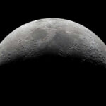 Half moon in a black sky with visible craters.
