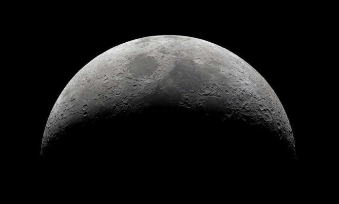 shutterstock_2149918359 Half moon in a black sky with visible craters.