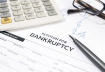 Bankruptcy petition form with pen, calculator, and eyeglasses