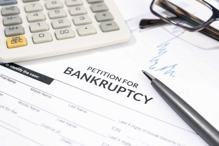 Bankruptcy petition form with pen, calculator, and eyeglasses