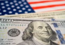 Close-up of a hundred dollar bill in front of an American flag