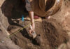 Archaeologist uncovering pottery at a dig site.