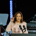 A woman speaks at a podium with microphones.