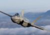 F-35 fighter jet flying above clouds with mountains in the background
