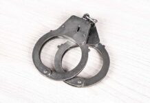 Locker Room Shock: Coach Arrested Fast A pair of metallic handcuffs resting on a light wooden surface