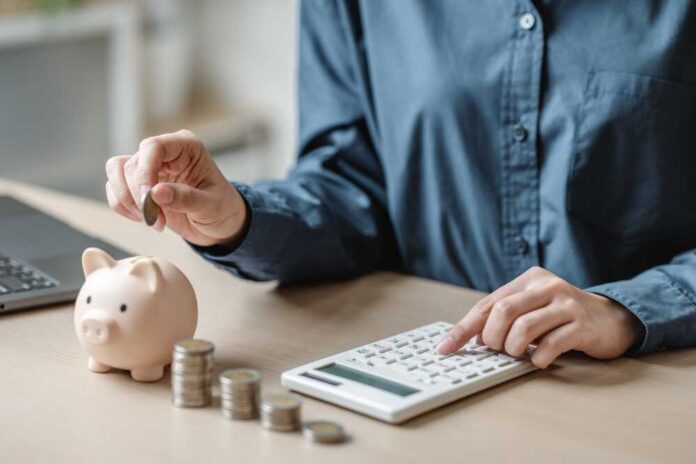 Saving,Money,Concept.,Savings,Banking,Finance.,Retirement,Planning.,Personal,Retire Person placing a coin into a piggy bank while using a calculator