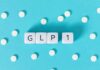 GLP-1 text on white cubes surrounded by white pills on blue background