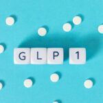 GLP-1 text on white cubes surrounded by white pills on blue background