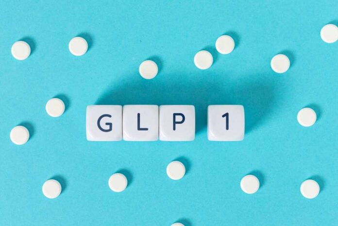 GLP-1 text on white cubes surrounded by white pills on blue background