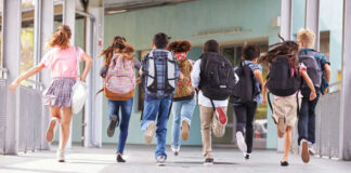 Children running with backpacks outside a school building.